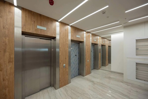 A modern elevator area with wooden paneling and a marble floor.