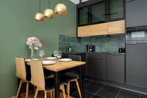 A modern kitchen with dark cabinetry, a wooden dining table, and three pendant lights.