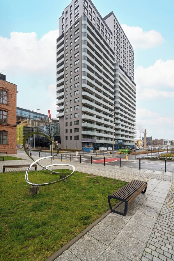 A modern high-rise building with a prominent spiral sculpture in the foreground.