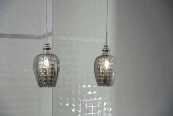 Two hanging glass pendant lights in a room with a geometric patterned wall.