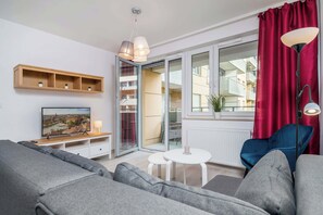 A modern living room with a sofa, TV, and a view through a glass door.