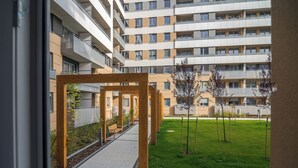 A modern building with a covered walkway, outdoor seating, and a grassy area with trees.