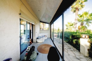 A modern outdoor living area with a glass wall, a white sofa, and a motorbike. - Family villa for 15 people with a playground, pool, and large hot tub! Ocean view!  (Tourrettes-sur-Loup)