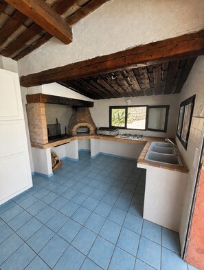 A kitchen with a built-in wood-fired oven, a sink, and a window providing natural light.