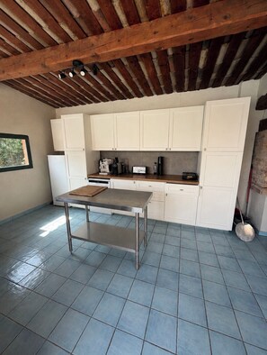 A kitchen with white cabinets, a stainless steel table, and a tiled floor.