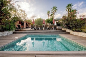 A swimming pool with lounge chairs and umbrellas, surrounded by greenery and palm trees. - Family villa for 15 people with a playground, pool, and large hot tub! Ocean view!  (Tourrettes-sur-Loup)