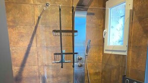 Une salle de bain moderne avec une douche à parois de verre, des toilettes et un porte-serviettes.