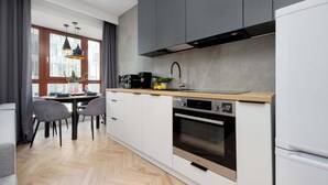 Una cocina moderna con armarios blancos, horno integrado y cafetera.
