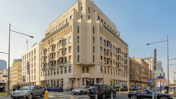 Un edificio de varios pisos con un diseño arquitectónico moderno, que cuenta con balcones y ventanas amplias.