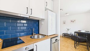 A modern kitchen with white cabinets, a blue backsplash, and a wooden countertop.