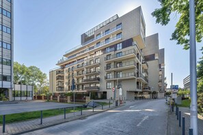 A multi-story residential building with balconies, a gated entrance, and a clear sky.