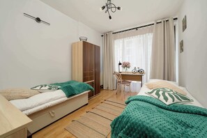 Camera da letto con due letti, una scrivania, un armadio e una bicicletta.
