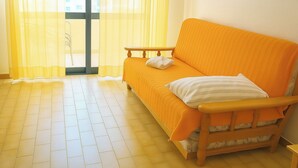 A room with a sofa, a window with sheer curtains, and a tiled floor. - Praia da Rocha 1 Bedroom Apartment With Balcony (Portimão)