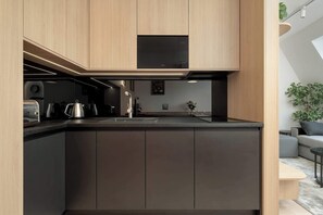 Une cuisine moderne avec des meubles en bois, un plan de travail noir et une cuisinière intégrée.