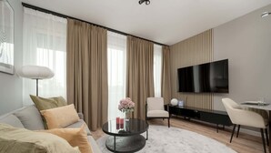 Ein modernes Wohnzimmer mit einer Couch, einem runden Couchtisch und einem Flachbildfernseher.