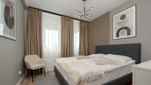 Ein Schlafzimmer mit Bett, Sessel, Vorhängen und einem Kunstwerk an der Wand.