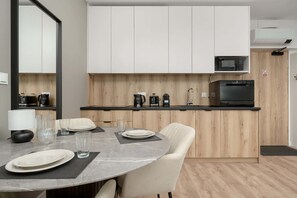 Una cucina moderna con mobili bianchi, un forno a microonde, una macchina da caffè e una lavastoviglie.