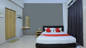 Habitación de hotel con una cama grande, una puerta de madera, una mesita de noche pequeña de madera, un espejo y una ventana con cortinas.