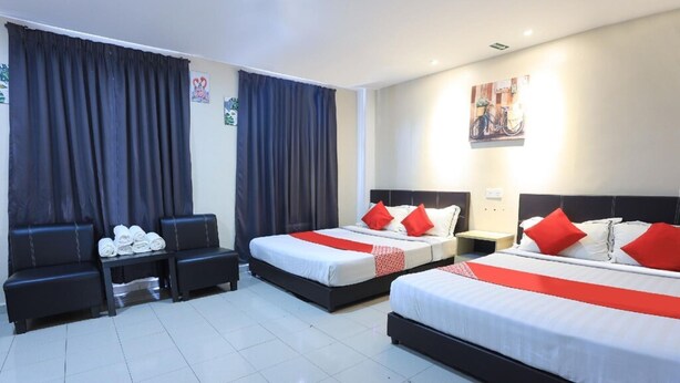 Habitación de hotel con dos camas, un pequeño rincón de descanso y baño.