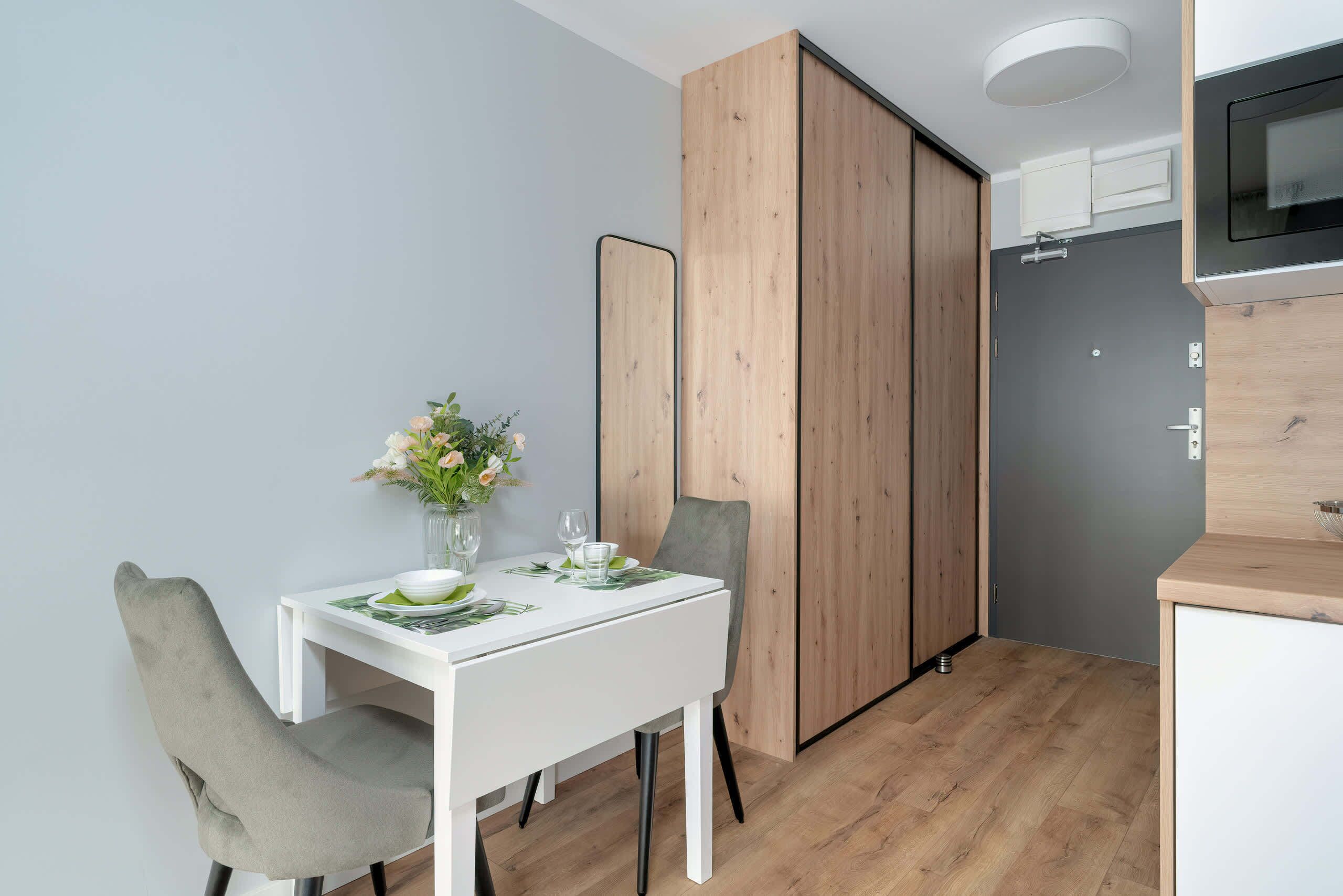 Una cocina compacta con microondas, un refrigerador pequeño y un armario de madera.
