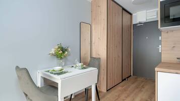 Una cocina compacta con microondas, un refrigerador pequeño y un armario de madera.