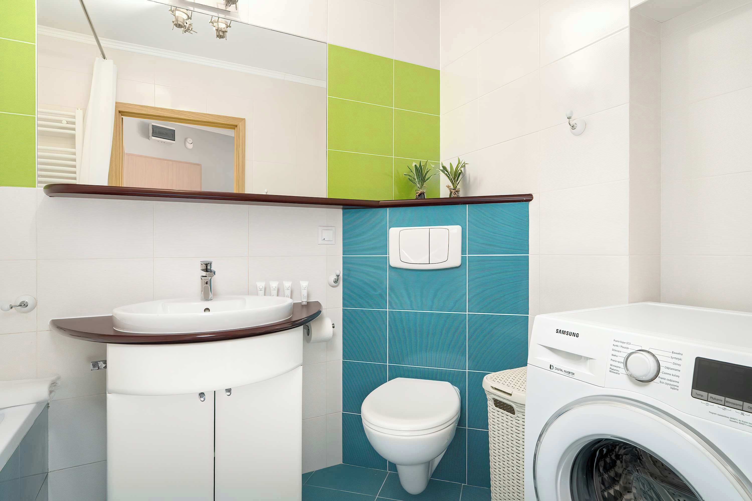 A modern bathroom with a sink, toilet, and washing machine.