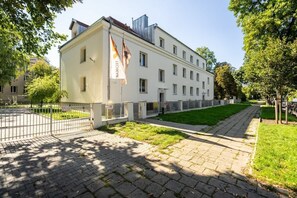 A building with a white facade, multiple windows, and a flag. - Poznan | Rycerska 5 | Spacious Apartment | Free Parking (Poznań)