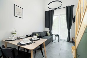 Een moderne, minimalistische kamer met een eettafel voor twee personen, een bank en een trap.