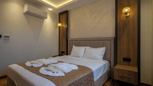 Ein ordentlich bezogenes Bett mit Handtüchern, einem Nachttisch und einer an der Wand befestigten Lampe.