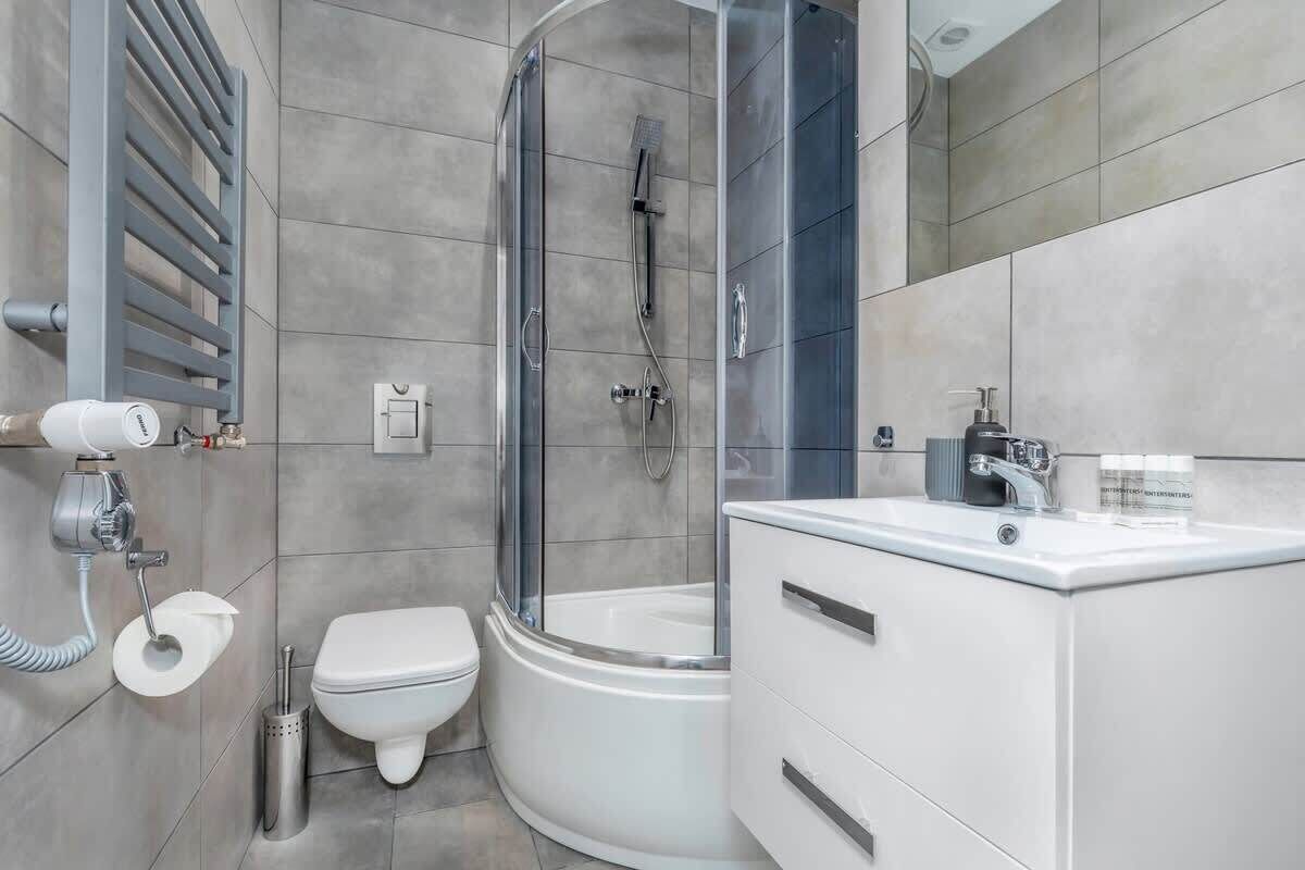 A modern bathroom with a glass-enclosed shower, a white toilet, and a vanity with a mirror.