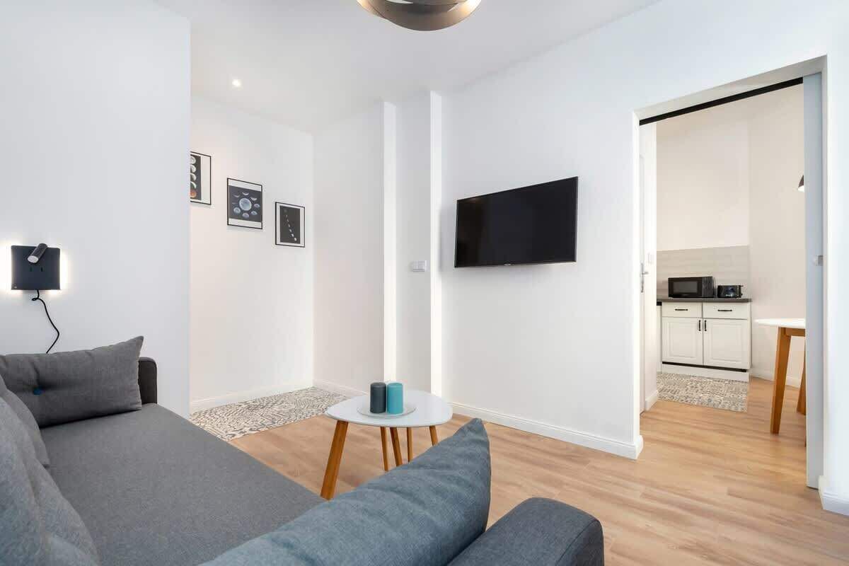 Un salon moderne avec un canapé, une petite table ronde et un téléviseur à écran plat fixé au mur.