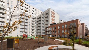 A playground with play structures, a bench, and a paved path in a residential area with apartment buildings. - Bright Apartment with Balcony | Parking, Workspace (Katowice)