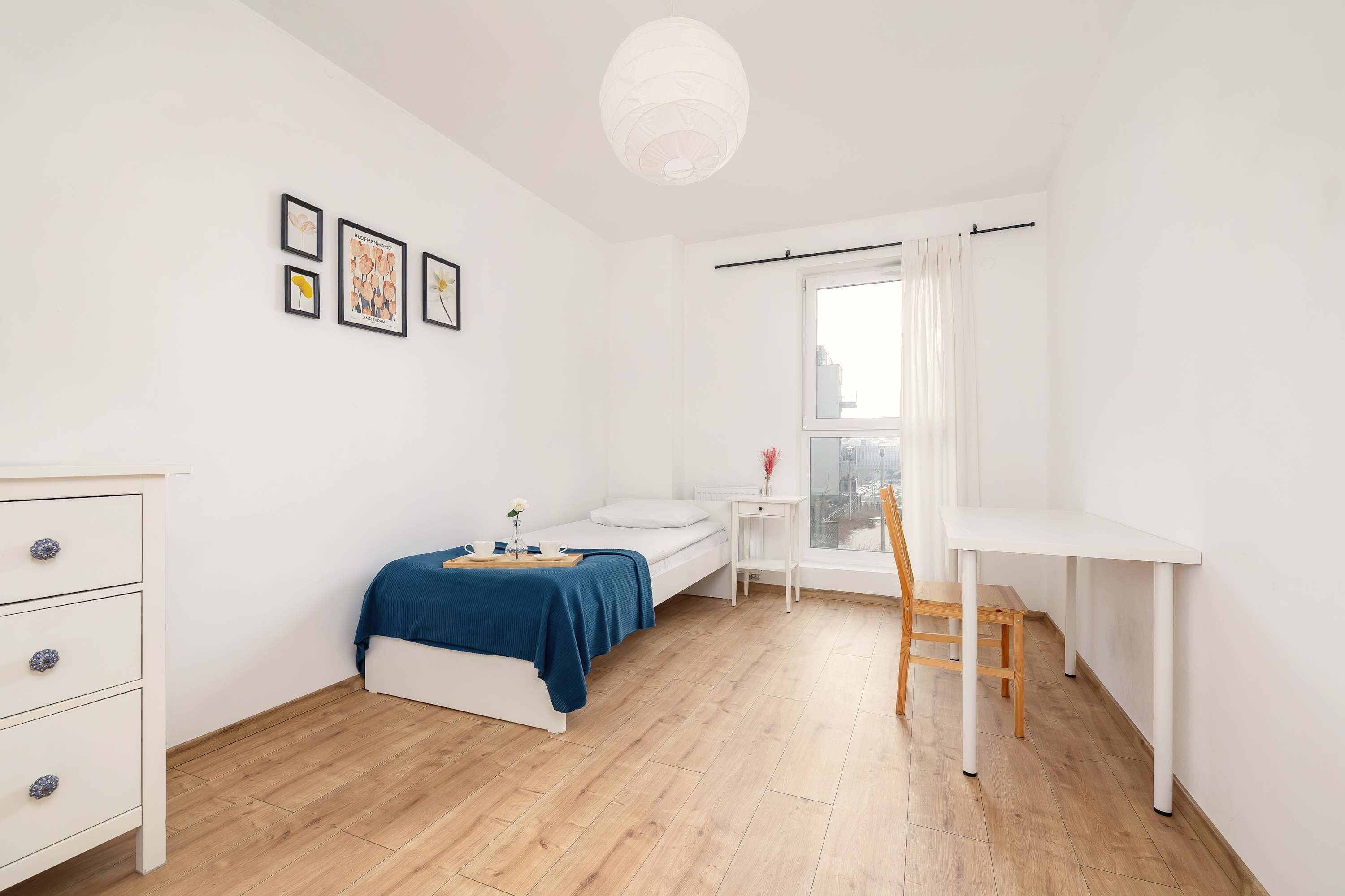 Une chambre à coucher au style minimaliste, comprenant un lit, une table de chevet et un bureau avec une chaise.
