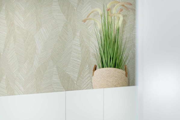 A potted plant with long green leaves and pale yellow flowers on a textured wall.