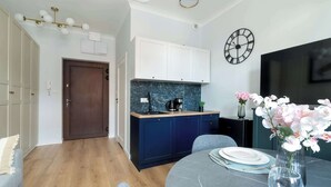 Een moderne keuken met donkerblauwe kastjes, een marmeren aanrechtblad en een klok aan de muur.