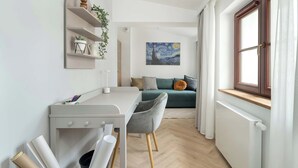 A modern, well-lit room with a desk, chair, and a green sofa. There is a painting on the wall and a window with curtains. - Spacious Apartment in the Center | Two Bedrooms | Desk. (Poznań)
