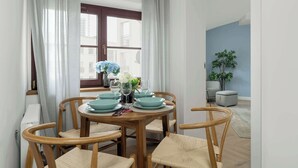 A dining area with a round wooden table set for four, surrounded by four wooden chairs with woven seats. - Spacious Apartment in the Center | Two Bedrooms | Desk. (Poznań)