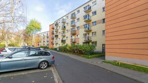 Un edificio residencial de varios pisos con balcones, un estacionamiento y un sendero para peatones.