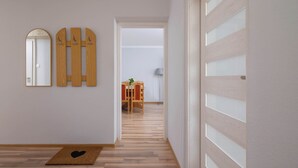 Un pasillo con piso de madera, un tapete con forma de corazón, un espejo y una puerta de madera con paneles de vidrio esmerilado.