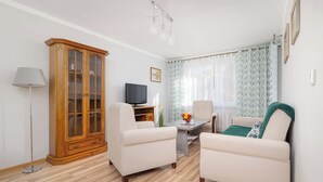 Una sala de estar con un mueble de madera, un televisor, una mesa con frutero y un sofá.