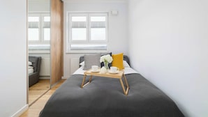 Un dormitorio con cama, mesita de noche y ventana.