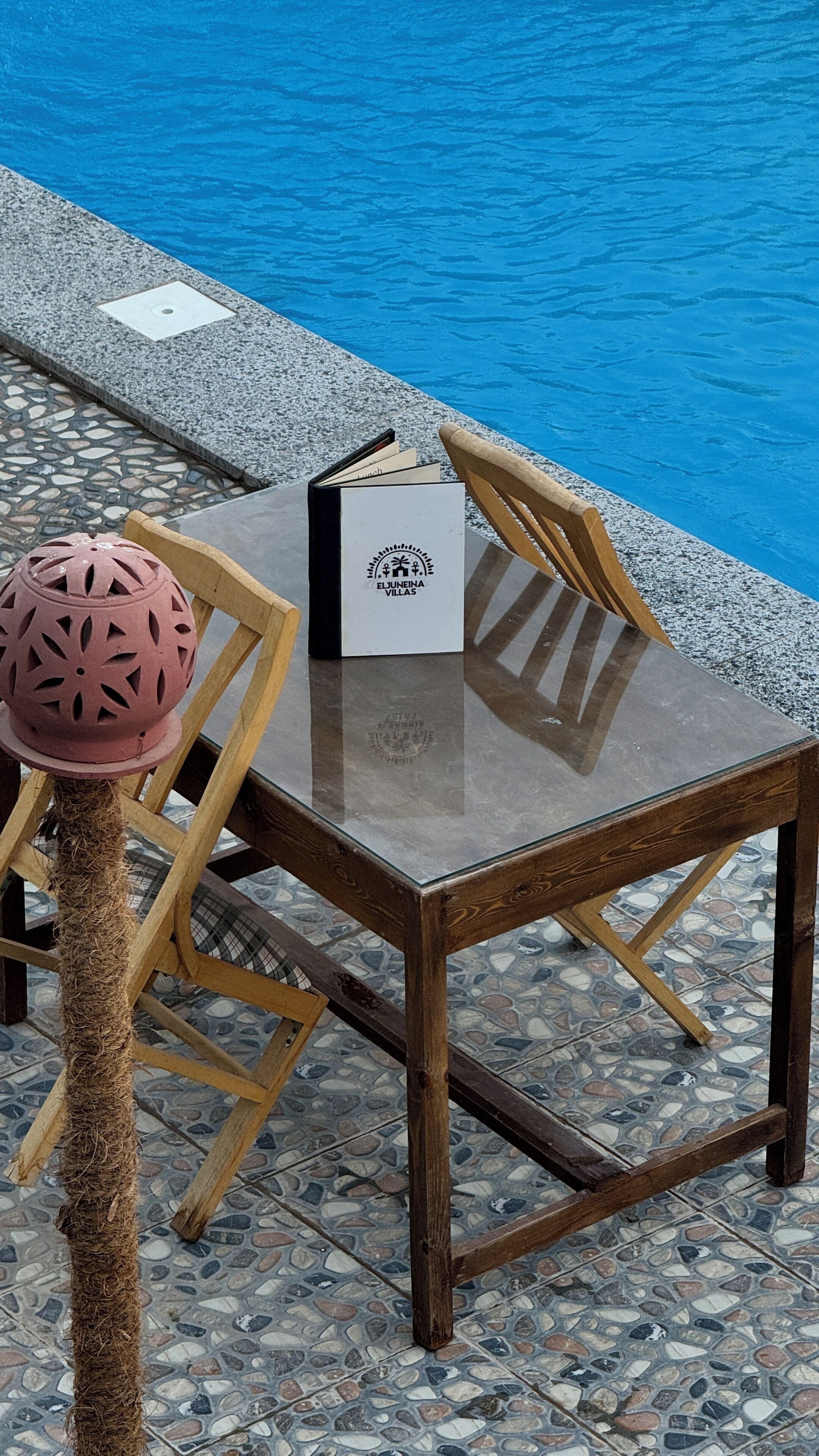 A table with a book and a decorative item by the poolside.