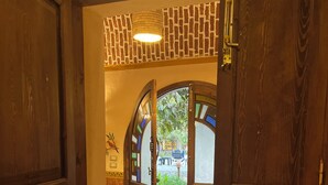 A wooden door leading to a room with a red rug and a chair. - Ramses Villa in ElJuneina Villas (Luxor)