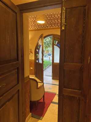 Una puerta de madera que da a una habitación con una alfombra roja y una silla.