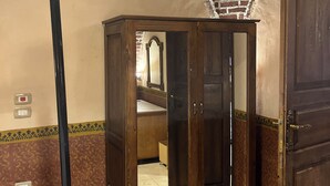 A room with a bed, a wooden wardrobe, a mirror, and a brick ceiling. - Ramses Villa in ElJuneina Villas (Luxor)