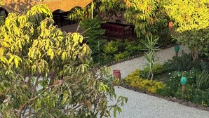 A garden pathway with a tiled area, surrounded by various plants and trees. - Ramses Villa in ElJuneina Villas (Luxor)