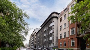 Une rangée d’immeubles résidentiels à plusieurs étages, avec des voitures garées le long de la rue.