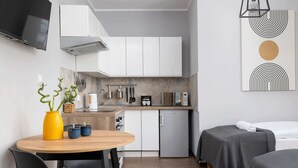 Une chambre d’hôtel compacte comprenant un coin cuisine, un espace repas et deux lits.
