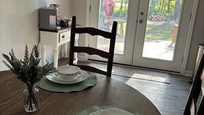 A dining area with a wooden table, chairs, and a glass door leading to an outdoor space. - Kayak Cove Lake Lagoon (Grant)