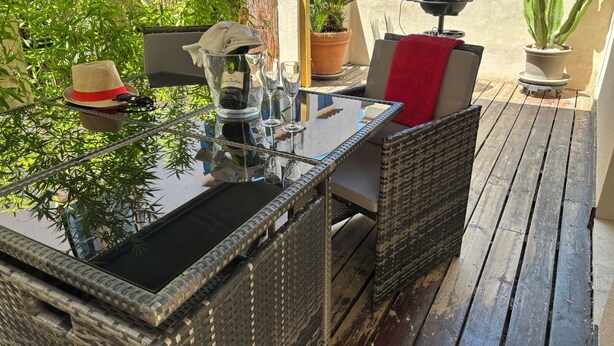 An outdoor patio with wicker furniture, a glass table, and potted plants. - Magnificent apartment on the outskirts of St Tropez (Cogolin)